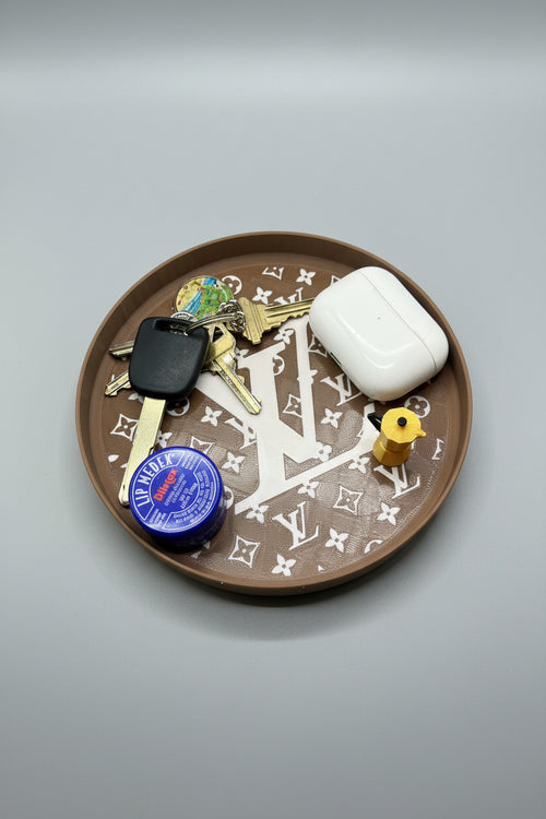 Round brown dish with keys, a mug, and a blue container on a gray surface