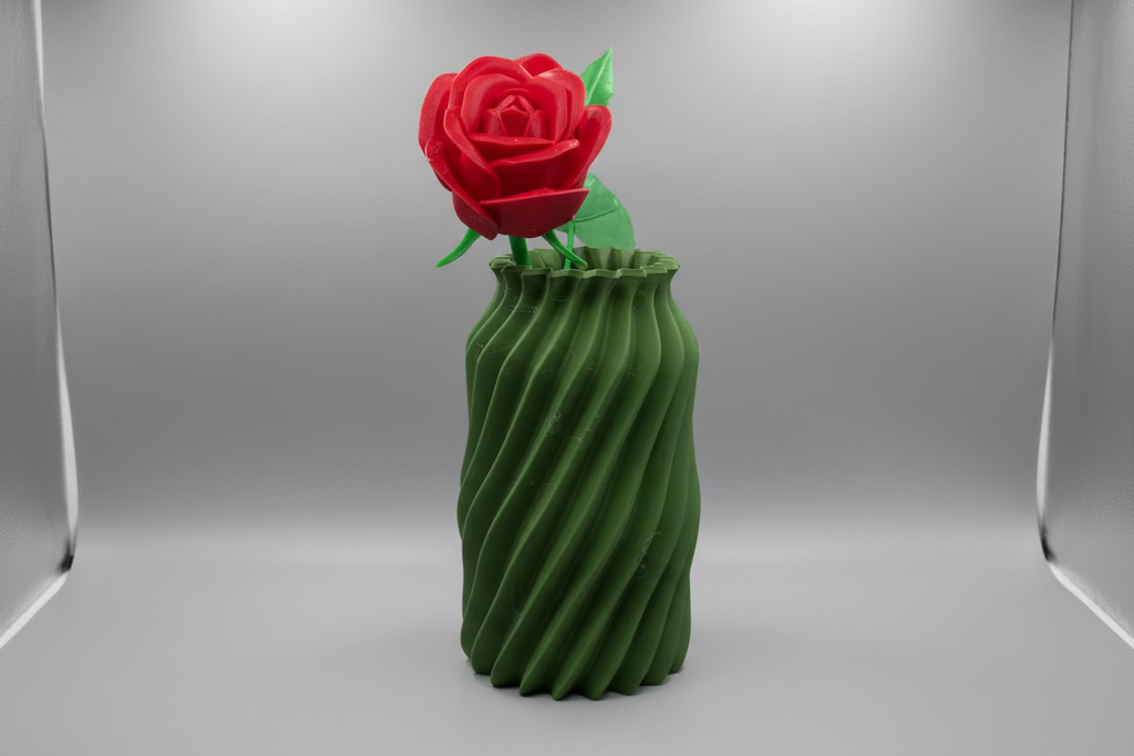 Green cactus-shaped vase with a red flower on a white surface