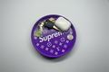 Purple round tray with 'Supreme' branding, keys, and a white air pod case on a gray surface.