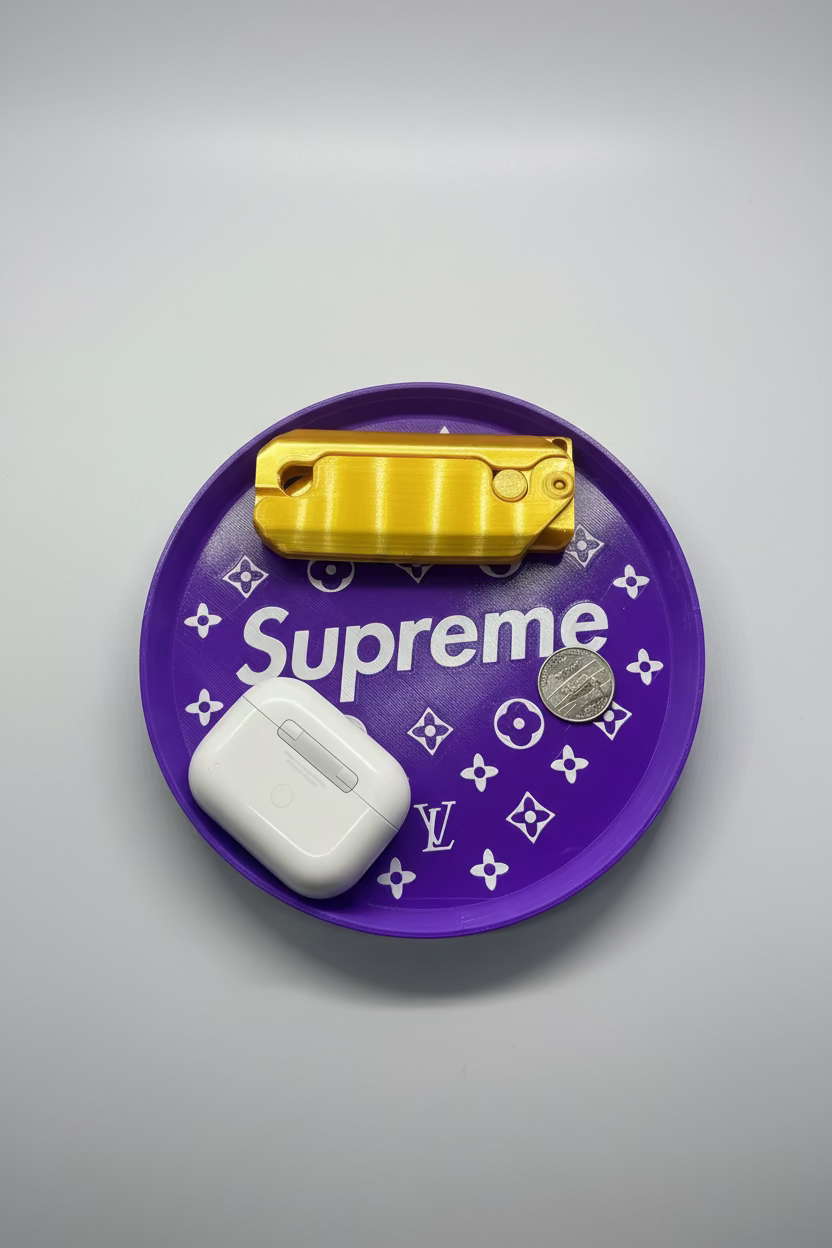 Purple plate with 'Supreme' branding, gold lighter, white case, and coin on a gray surface.