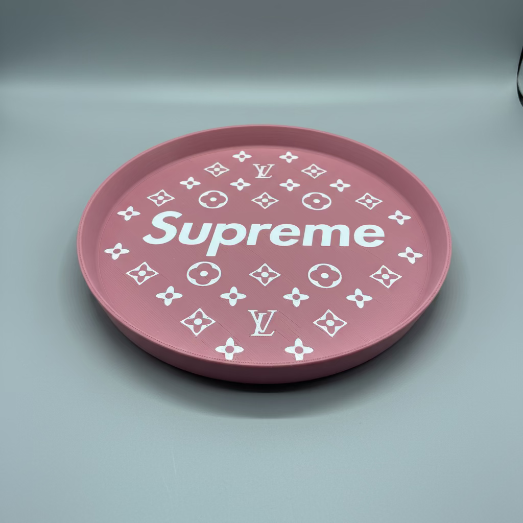 Pink circular object with 'Supreme' text and Louis Vuitton logo patterns on a dark surface.