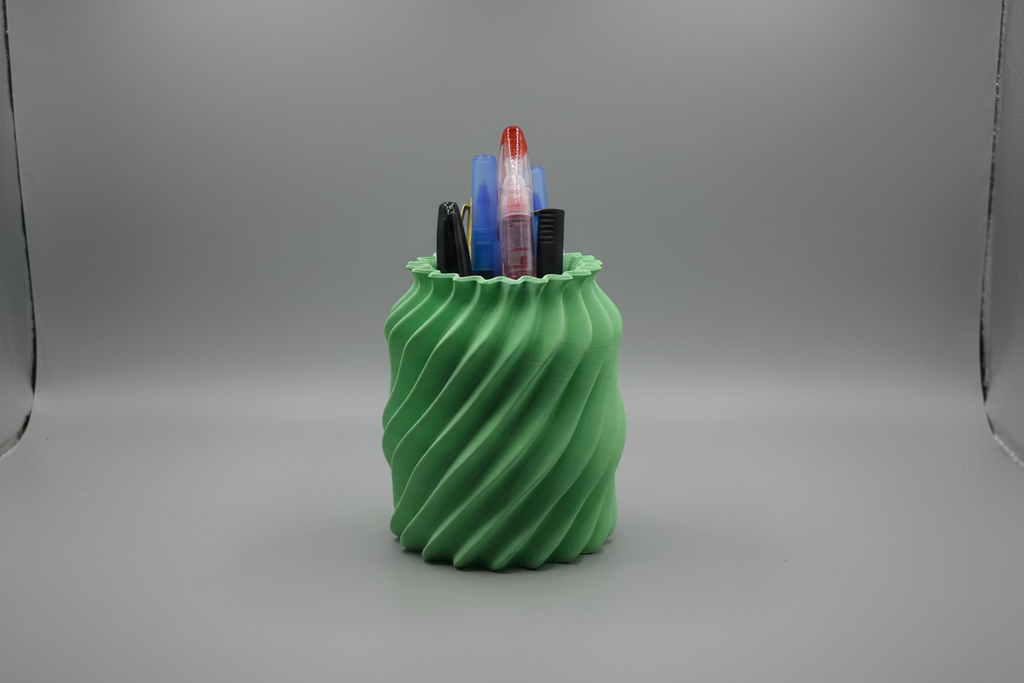 Green spiral pen holder with markers on a white surface