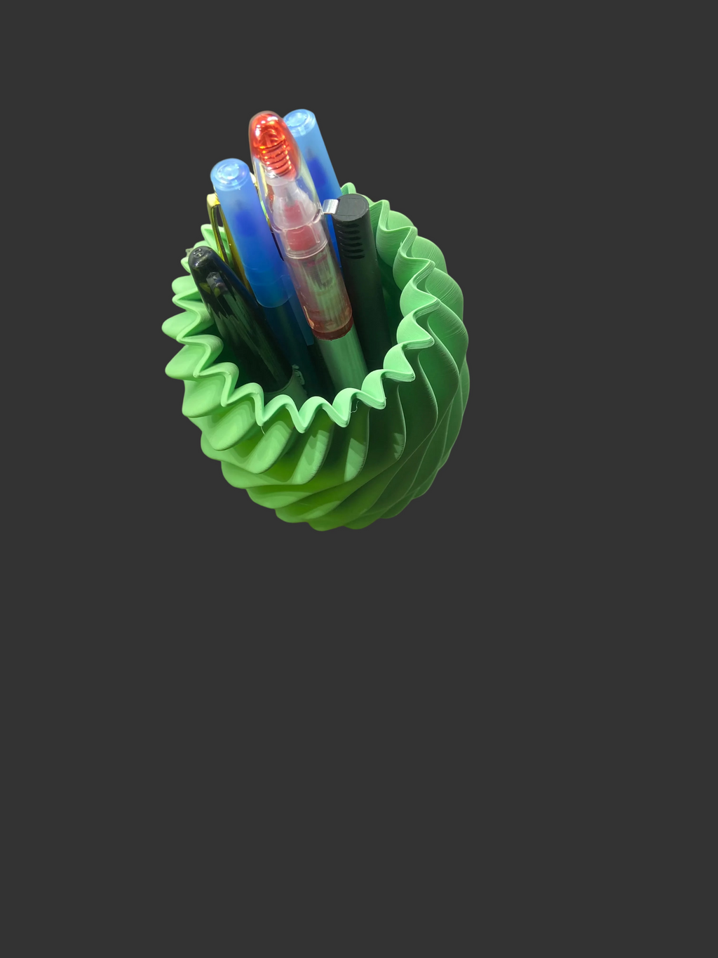 Green spiral pen holder with pens and markers on a desk