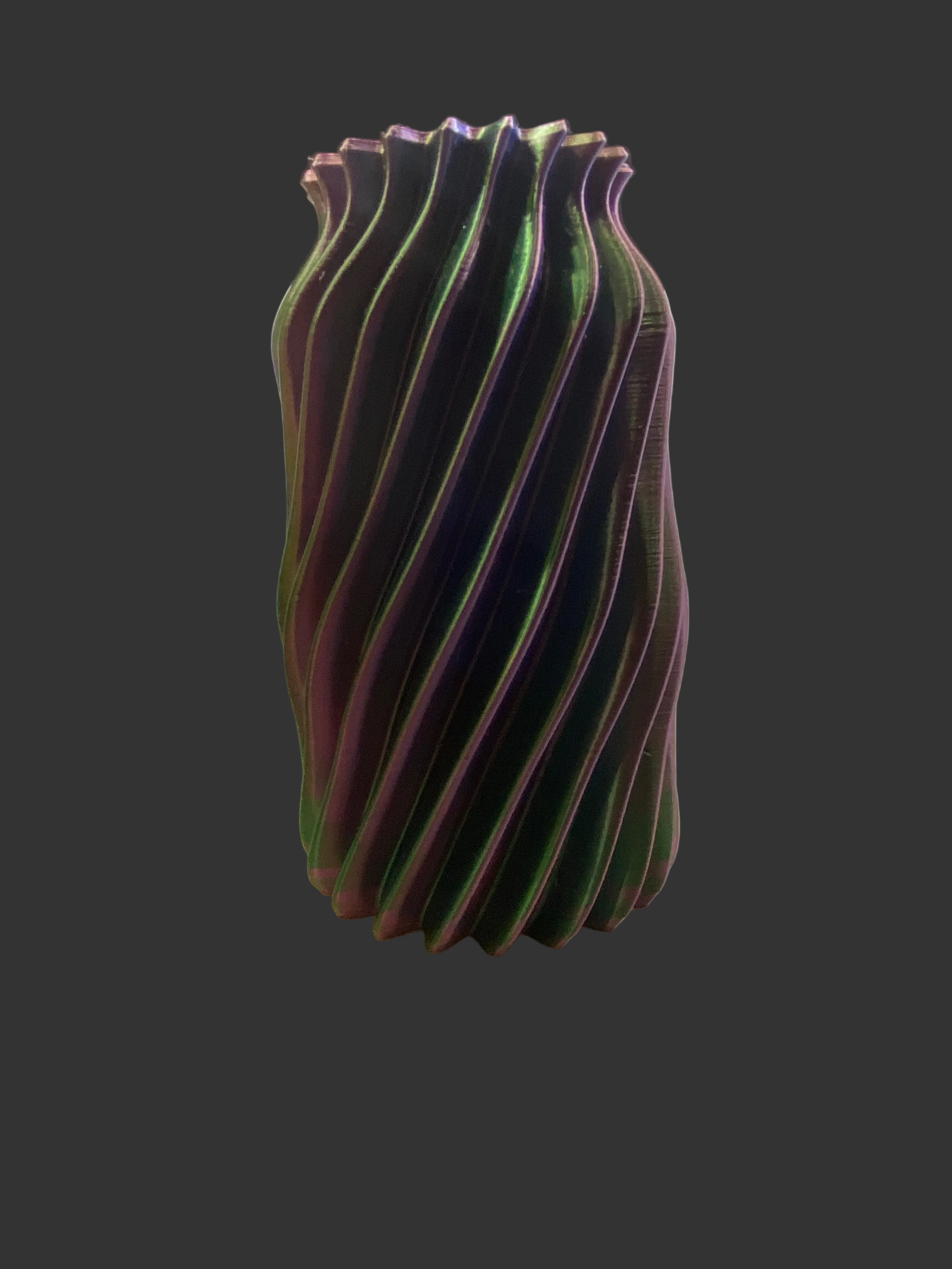 Vibrant purple and green vase on a white pedestal against a dark background