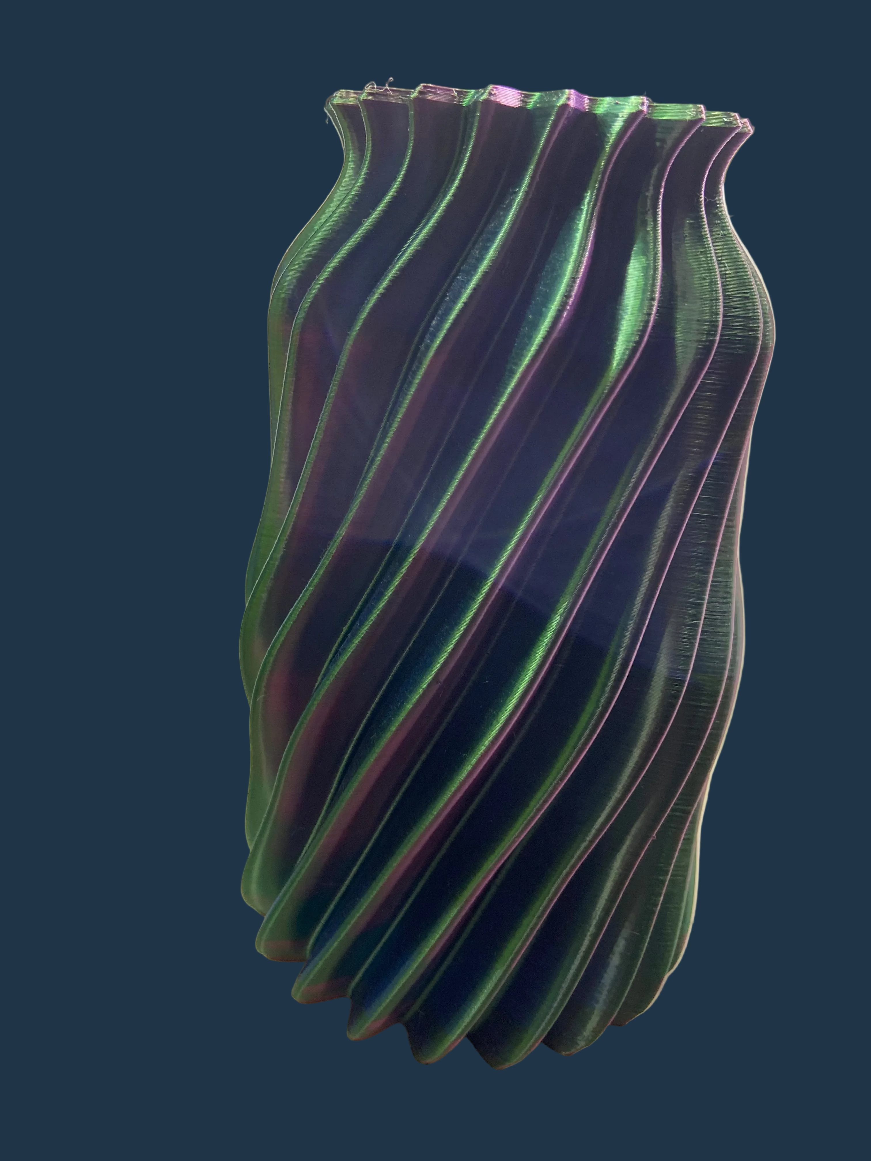 Green and purple striped vase on a white surface