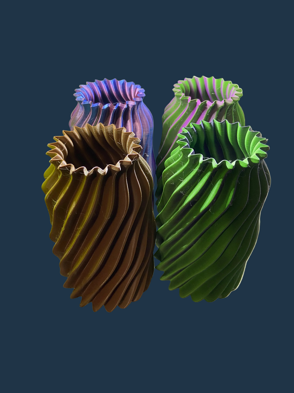 Four colorful 3D-printed vases on a white surface with a light gray background.