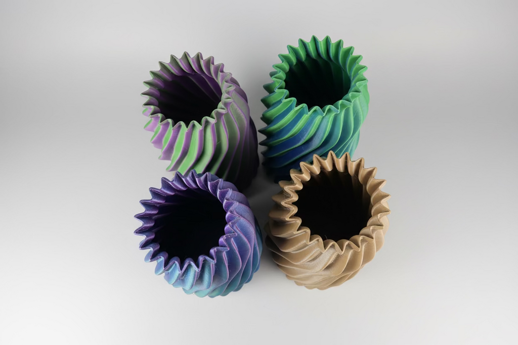 Three colorful paper cups with wavy edges on a white surface.