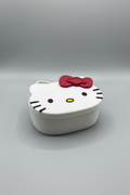Hello Kitty face-shaped object with a red bow on a dark surface