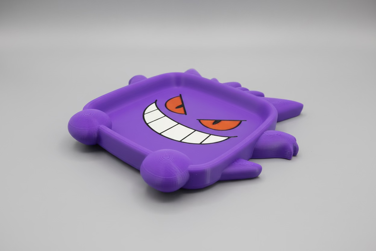 Purple 3D-printed object with a cartoonish face design on a green surface
