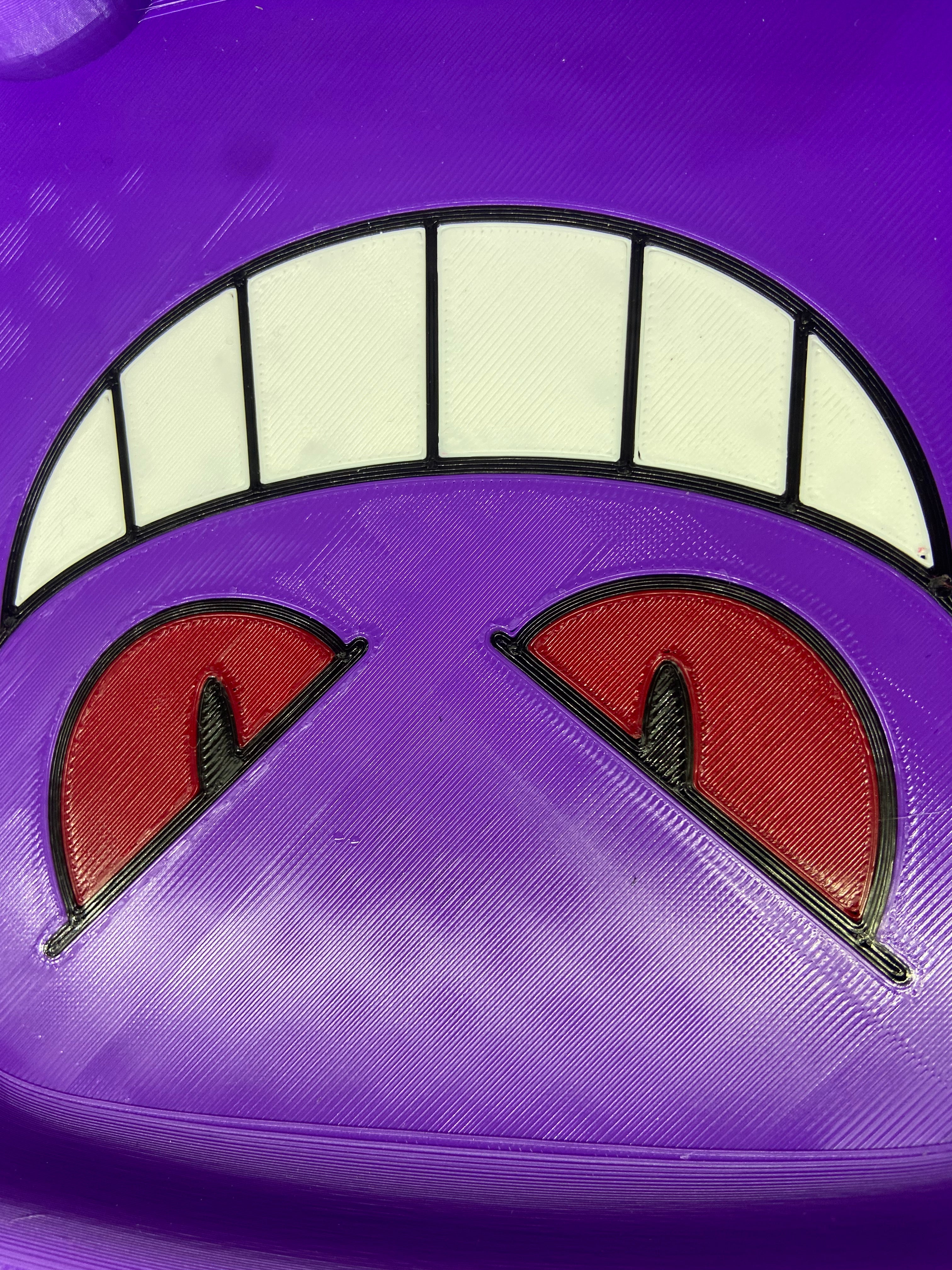 Close-up of a purple helmet with cartoonish eyes and mouth design.