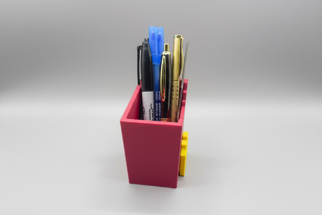 Collection of pens and markers in a pink holder on a gray surface