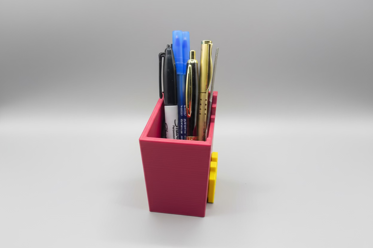 Collection of pens and markers in a pink holder on a gray surface