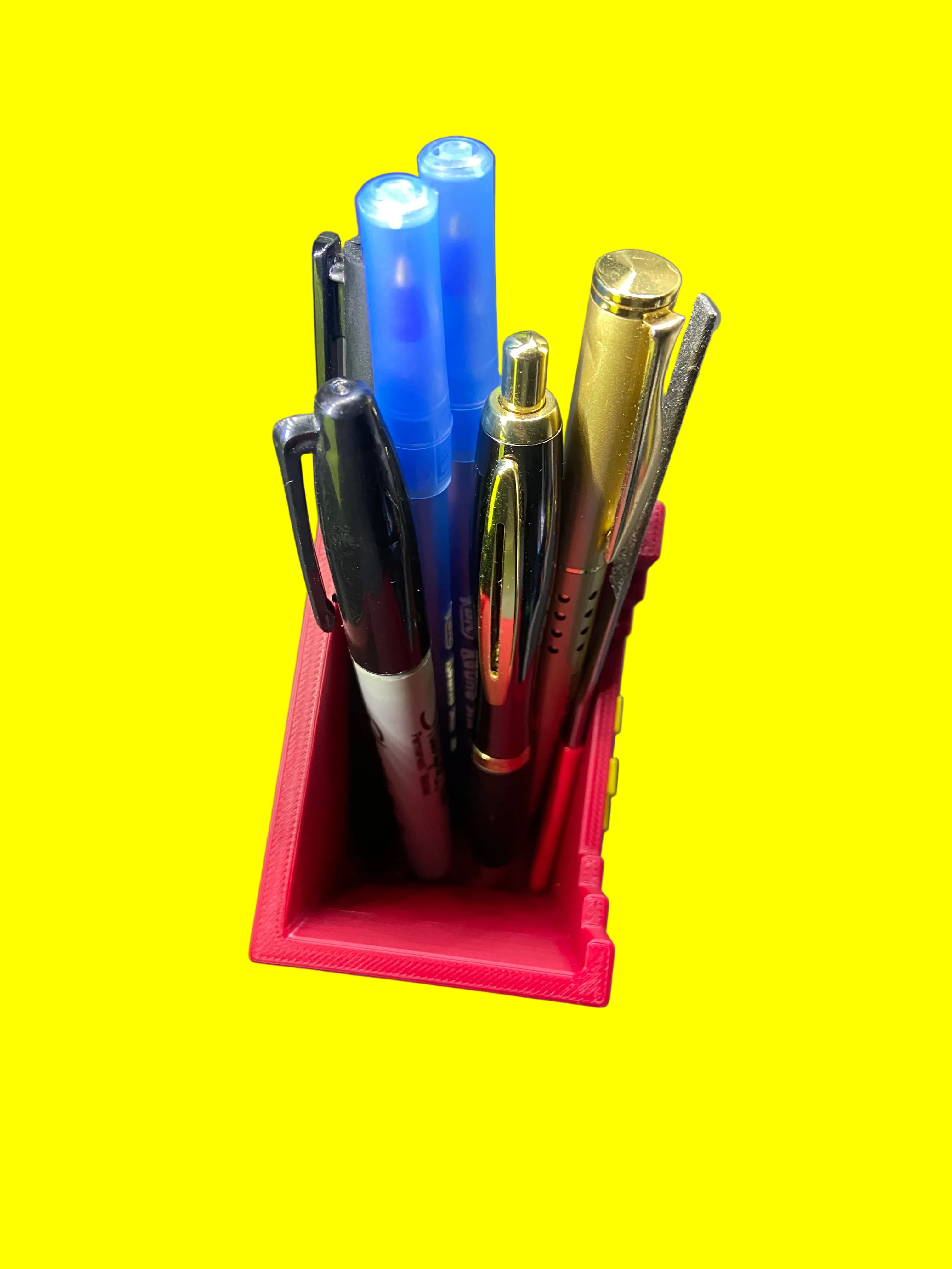 Collection of pens in a red holder on a gray surface