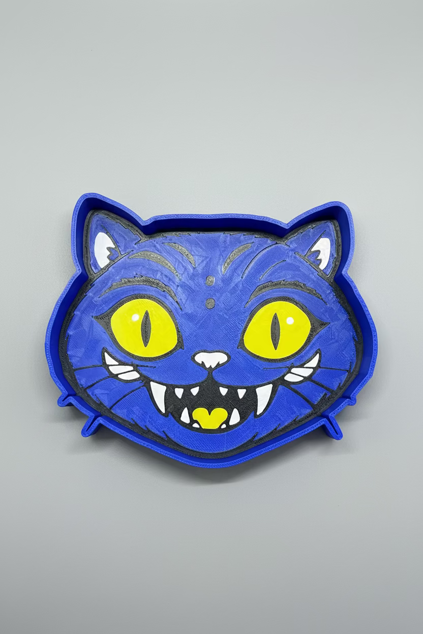Blue cat-shaped cookie cutter with yellow eyes and a heart on a gray background