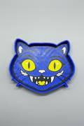 Blue cat-shaped cookie cutter with yellow eyes and a heart on a gray background