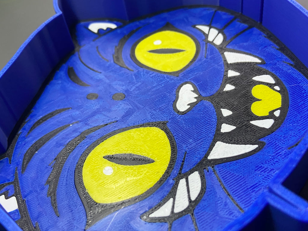 Blue toy with yellow eyes and black accents on a blue background