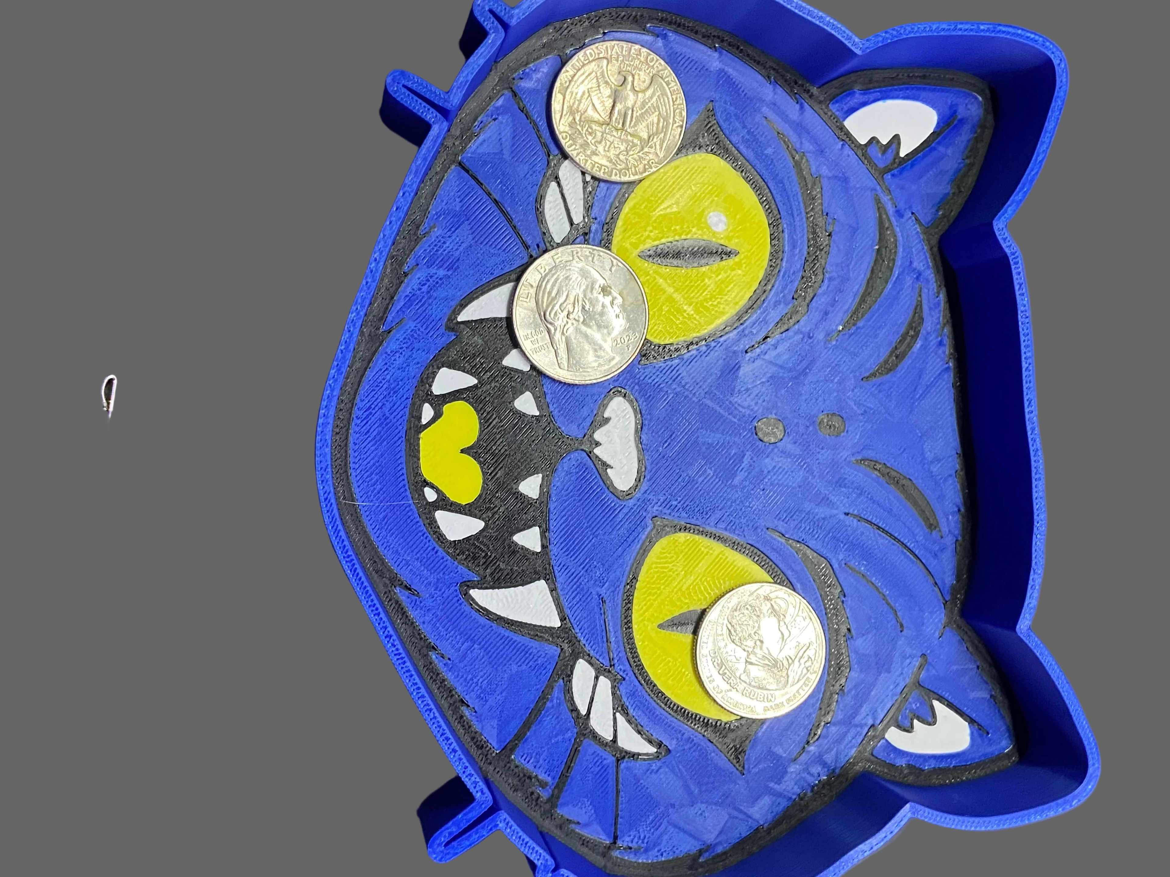 Blue cat-shaped coin purse with coins on a gray background