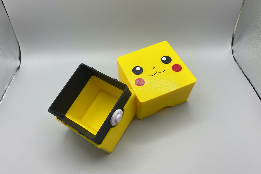 Yellow and black device with a cartoon face on a gray surface